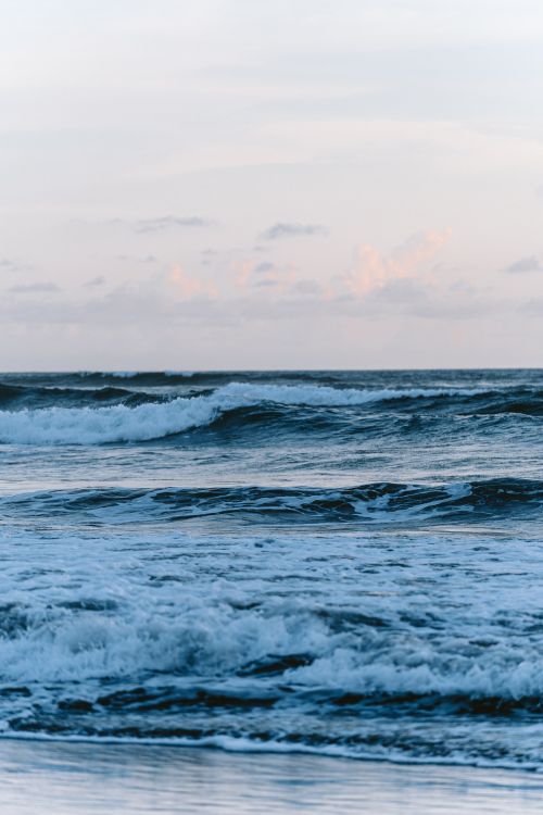 Free Beautiful view of waves crashing on Pulukan Beach, Bali at twilight. Perfect coastal landscape for calming visuals. Stock Photo