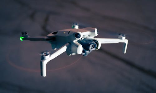 A small white drone flying in the air