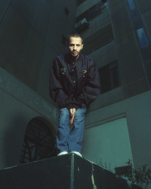 A man sitting on top of a ledge in front of a building