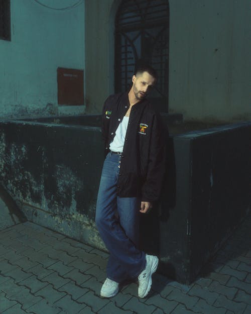 Man in Black Jacket and Jeans Posing on Sidewalk