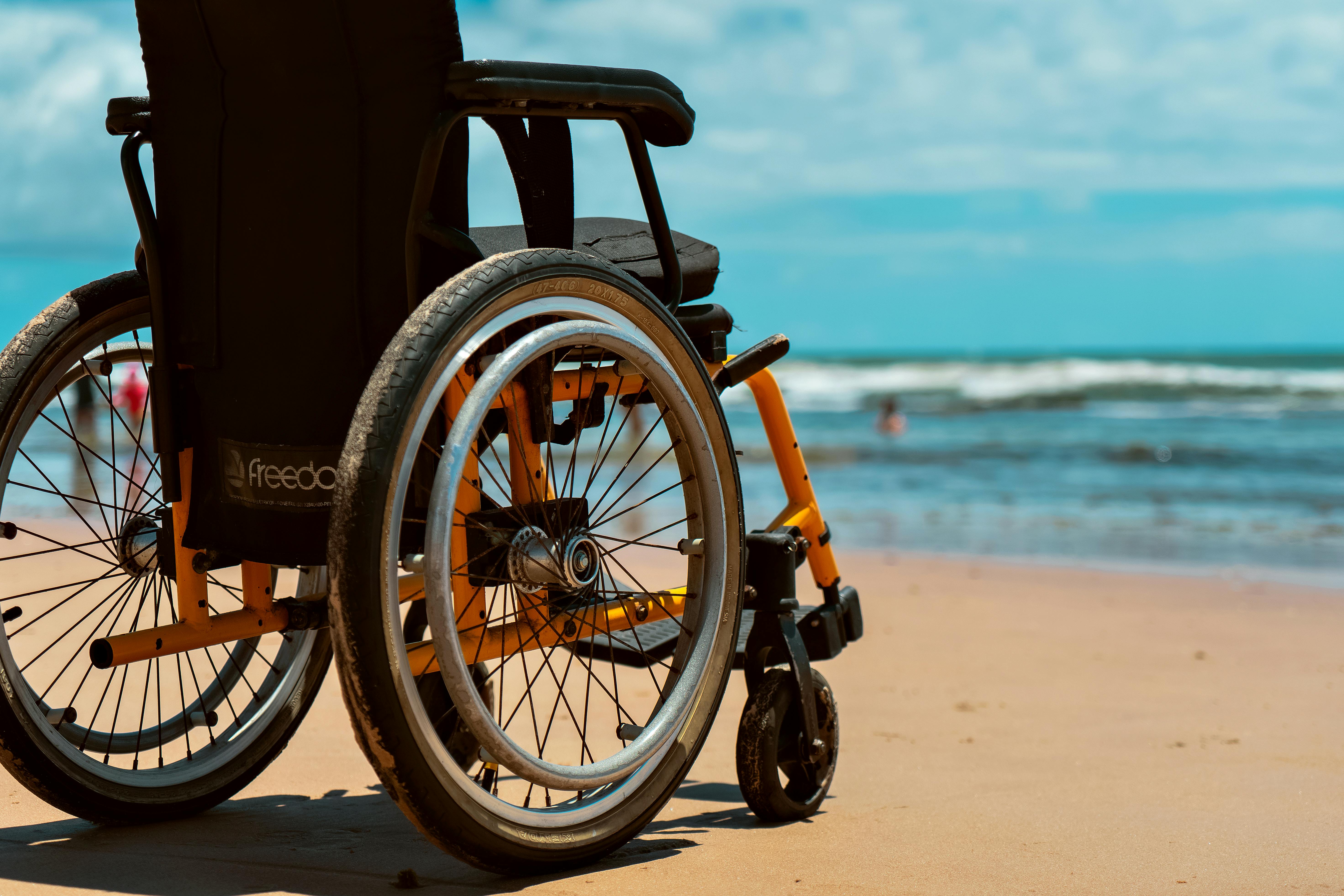 A vibrant beach scene featuring a wheelchair on the sandy shore with a view of the ocean waves.