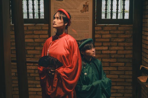 Two women in traditional clothing standing in front of a brick wall