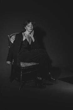Black and white portrait of a woman elegantly posing in a studio setting.