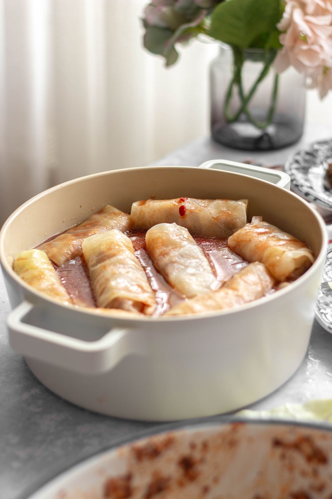 Uncooked cabbage rolls arranged in a Dutch oven partially submerged in tomato sauce, ready to simmer