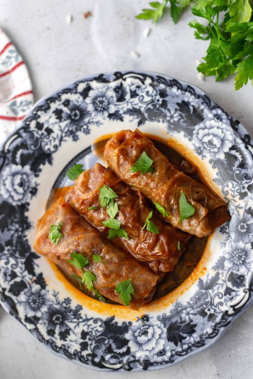 Free Top view of savory stuffed cabbage rolls garnished with herbs on a decorative floral plate. Stock Photo