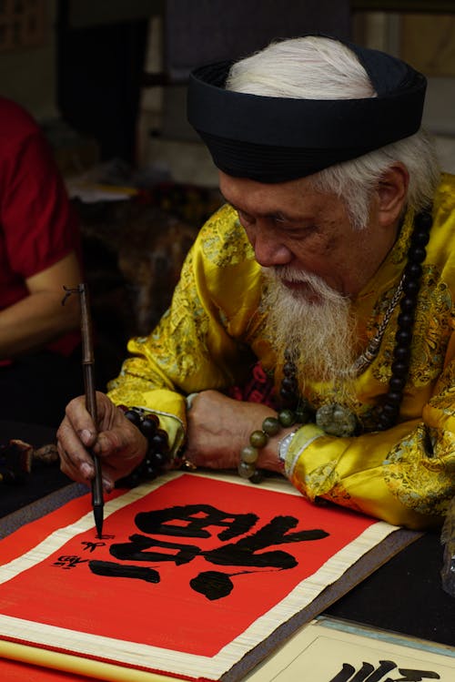 Elderly Man Painting Signs in a Temple 