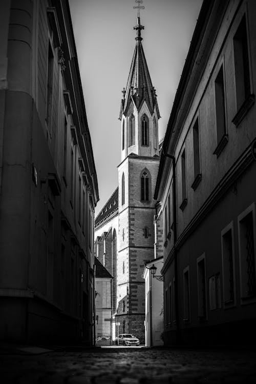 A black and white photo of a church in a narrow alley