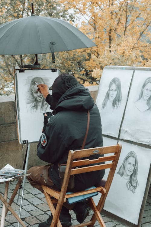 Back View of a Man Drawing Portraits on a Street 