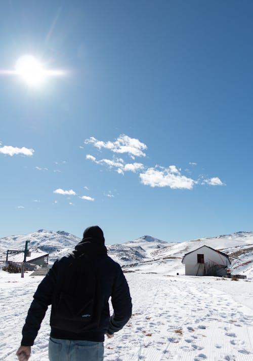 Man in Jacket with with Backpack Walking in Village in Winter