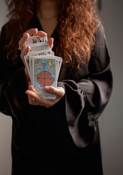 Free Close-up of a woman in black dress holding tarot cards, symbolizing spirituality and divination. Stock Photo