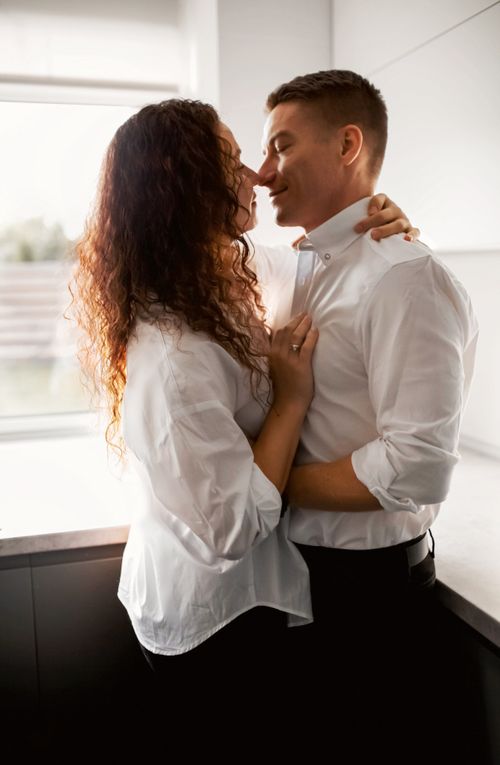 Free A loving couple embracing in a bright kitchen, showcasing intimacy and affection. Stock Photo