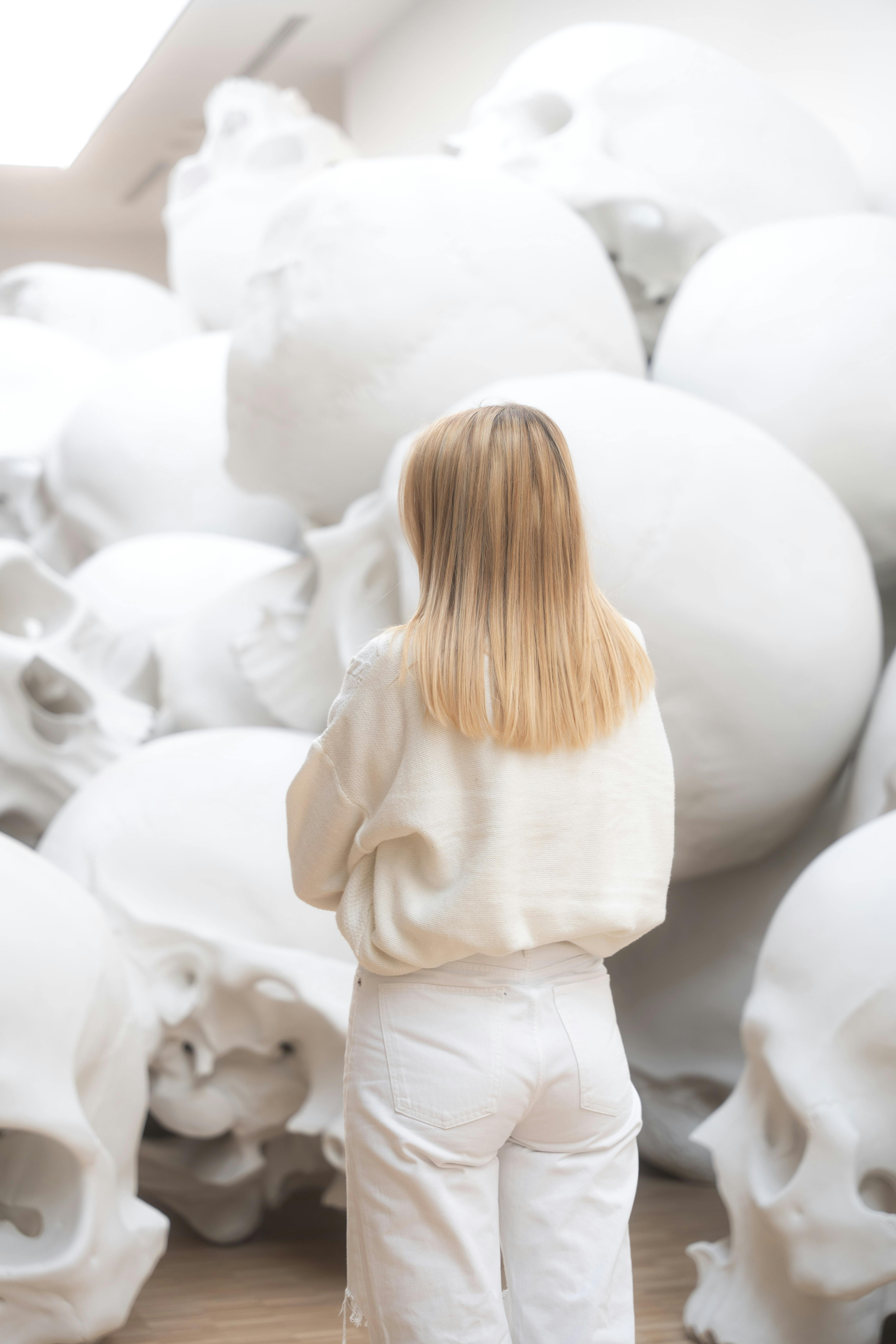A woman stands among large white skulls at an art exhibition in Milan, Italy.
