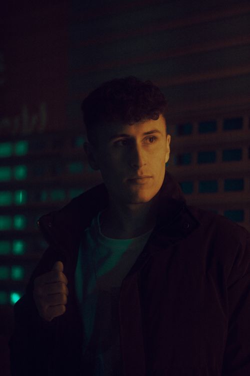Free Portrait of a young man looking away in a dark, serene night setting. Stock Photo
