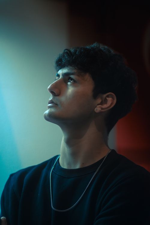 Free Portrait of a young man gazing upward, embodying contemplation and fashion style. Stock Photo