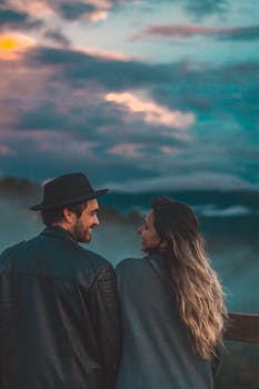 一对夫妇凝视着日落，周围是美丽的云彩和大自然