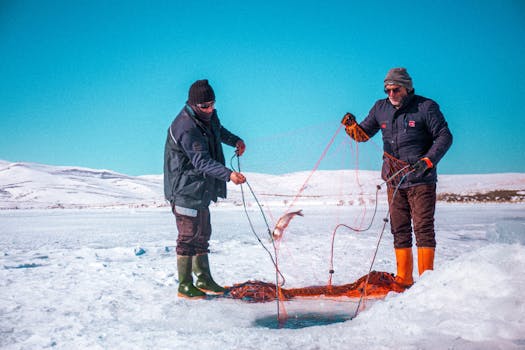 Two fishermen ice fishing on a frozen lake in Kars, Türkiye during winter.