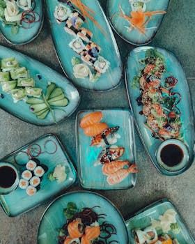 Top view of assorted sushi rolls and sashimi on blue plates. Vibrant and appetizing.