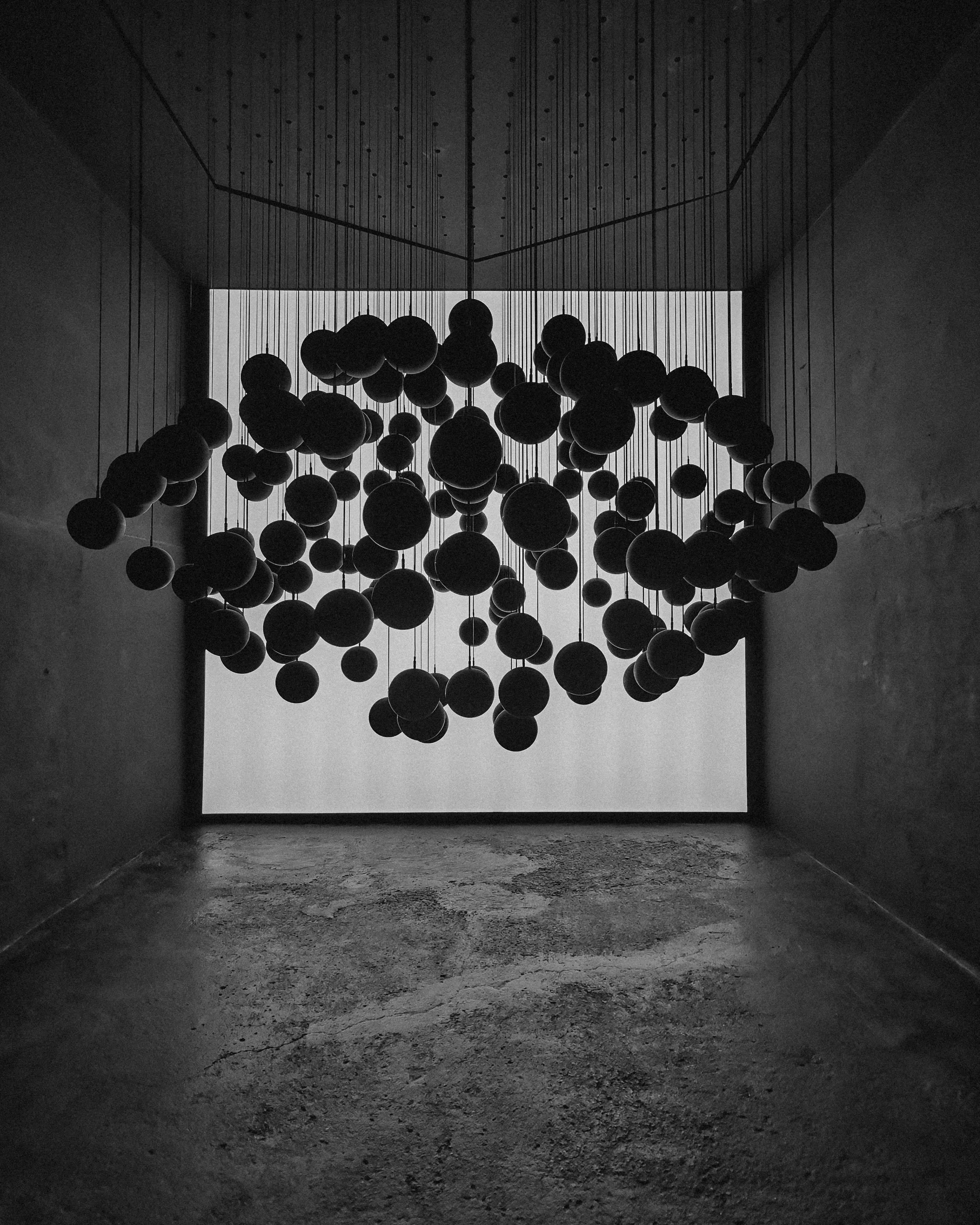 Minimalist black spheres hanging in a modern exhibition room.