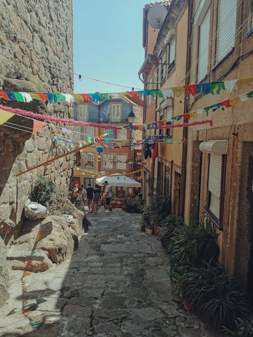 A narrow street with colorful bunting hanging from the buildings