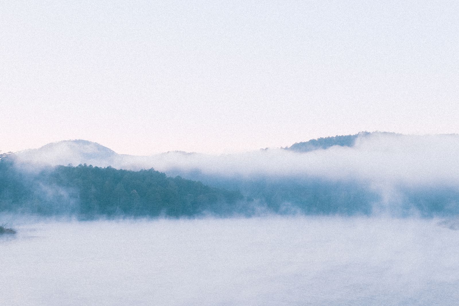 Peaceful foggy lake scene with mist-covered trees and hills, evoking tra — Photo by Thanh  Luu on Pexels