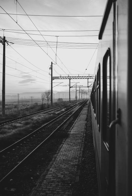A dramatic black and white view of a passenger train traveling down the tracks.