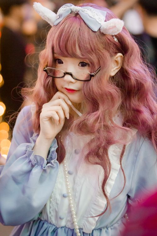 Free Whimsical cosplay portrait featuring a young woman in a cute pastel outfit and glasses. Stock Photo