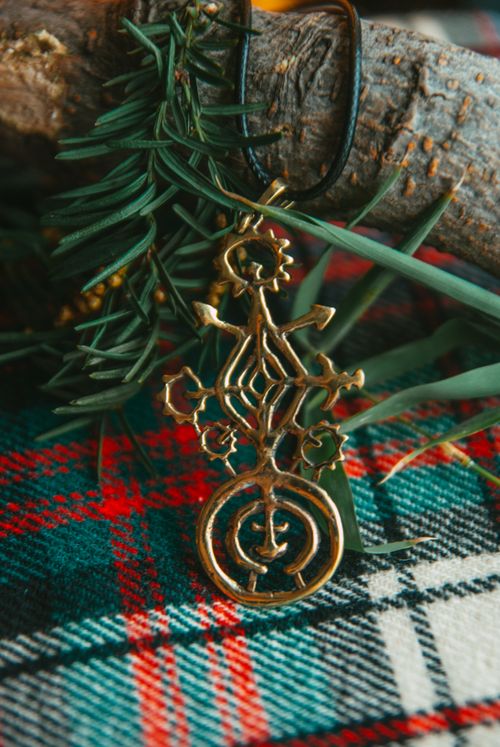 Free Close-up of a golden pendant on a tartan blanket with pine needle decoration, evoking a festive Christmas feel. Stock Photo