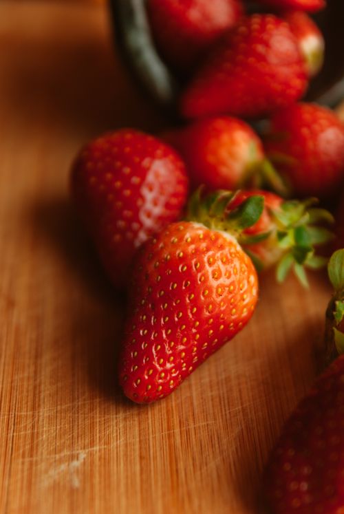 Free Close-up of ripe strawberries on a wooden surface, showcasing vibrant red colors. Stock Photo