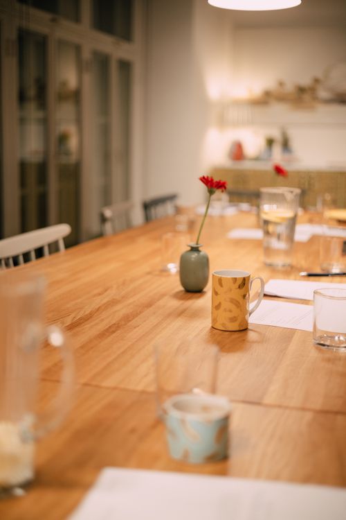 Free Warm indoor dining setting featuring wooden table, vase, and scattered mugs. Stock Photo