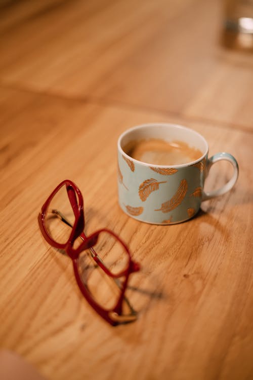 A cup of coffee and glasses on a table