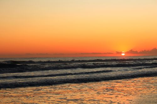 Free A tranquil sunset casts vibrant hues over the waves at Guaratuba Beach, Brazil. Stock Photo