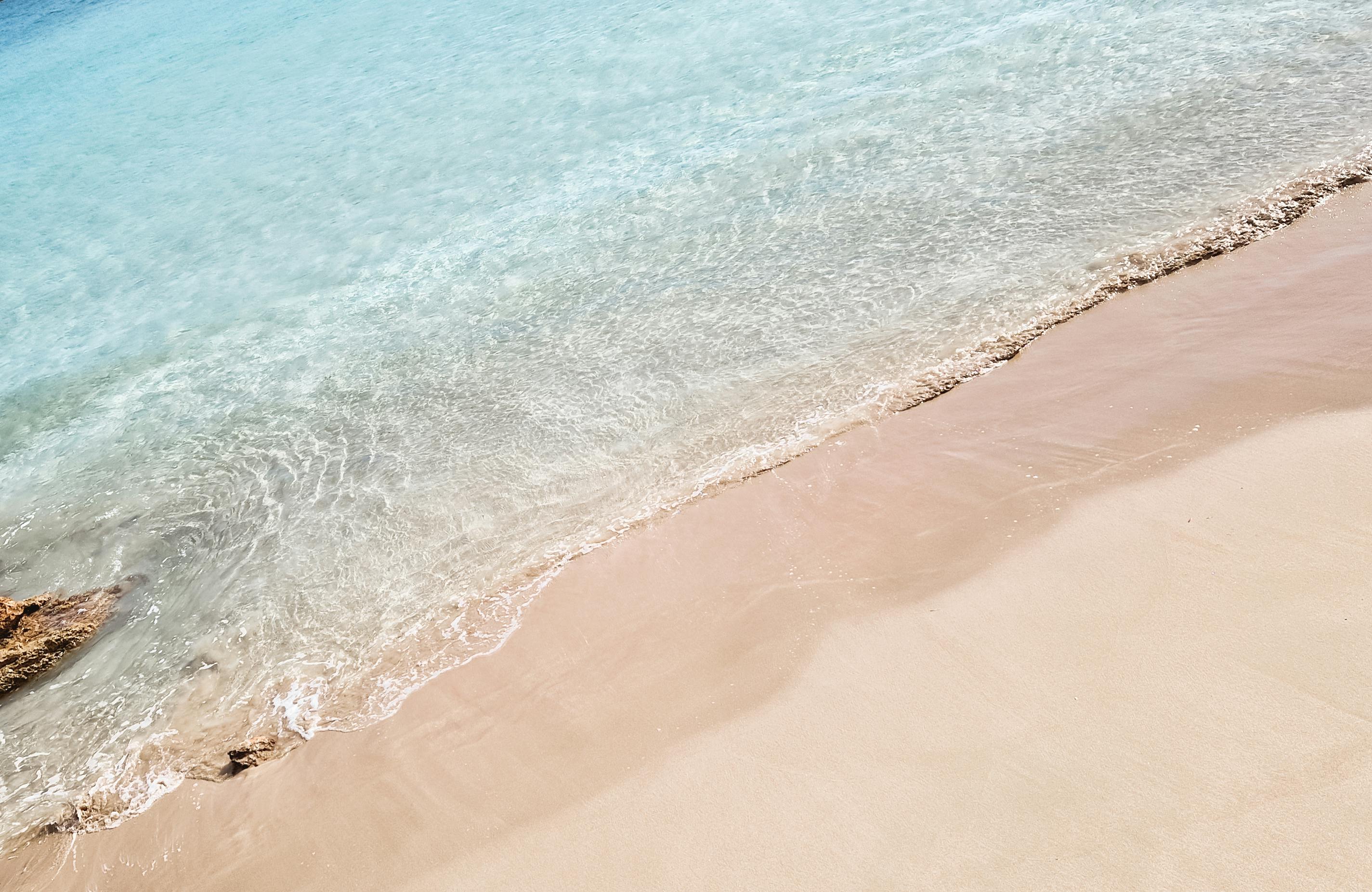 A serene view of gentle waves lapping onto a sandy beach at Koufonisia, Greece.
