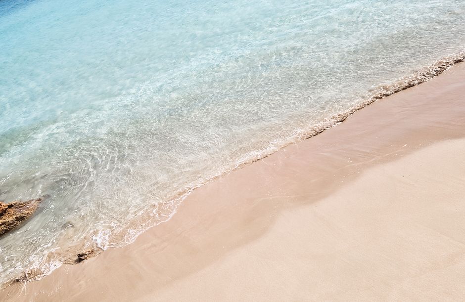 A serene view of gentle waves lapping onto a sandy beach at Koufonisia, Greece.