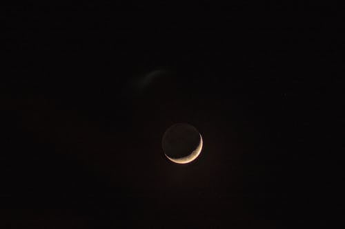 A crescent moon is seen in the dark sky