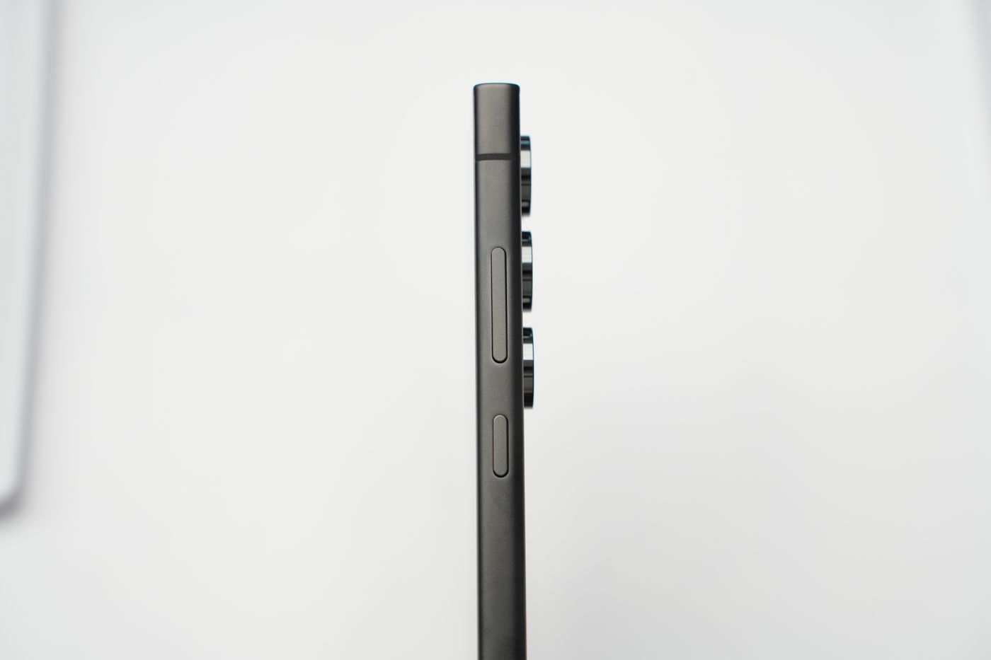 Side profile of a slim smartphone against a pale background, showing how thin the body is