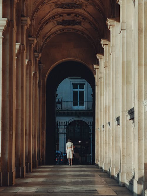 Woman in White Dress Standing in Cloister of Louvre Museum in Paris, France