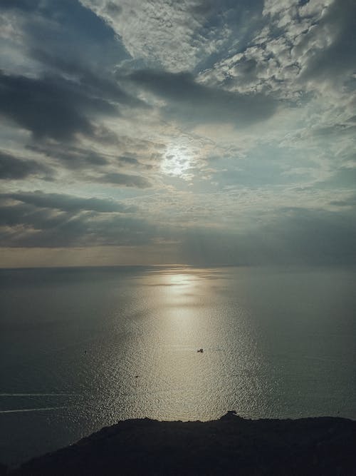 A boat is seen in the ocean under a cloudy sky