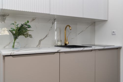 Free Elegant kitchen interior with marble counters and a gold faucet, featuring greenery for a touch of nature. Stock Photo
