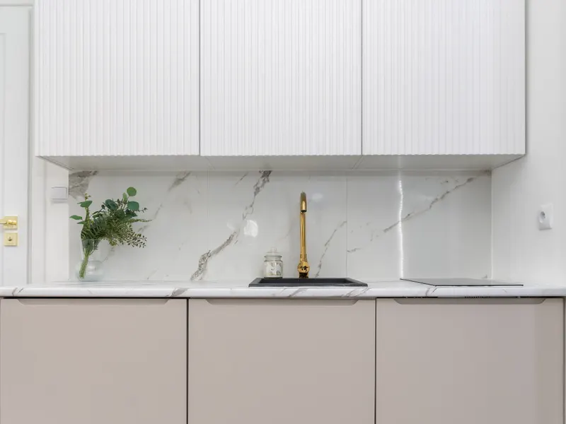 Minimalist luxury kitchen with a marble backsplash and golden faucet Minimalist luxury kitchen with a marble backsplash and golden faucet