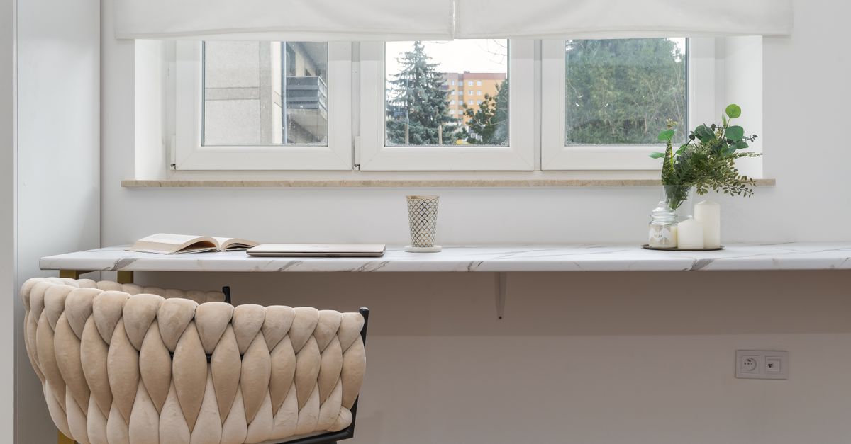 Elegant indoor scene featuring a comfortable armchair, a sleek white desk, and houseplants.