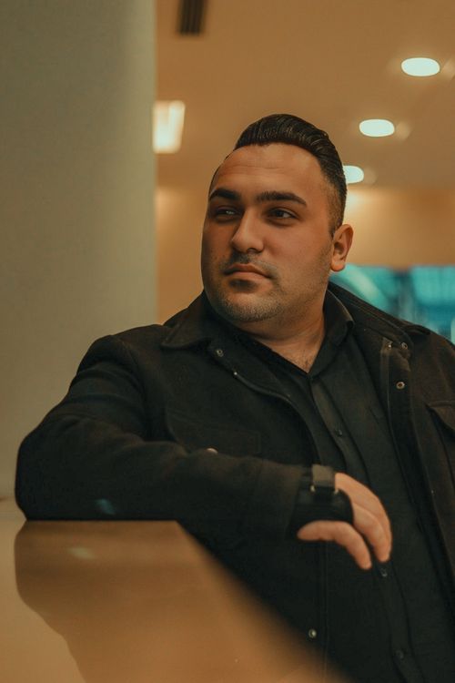 Free Middle-aged man in a black jacket posing indoors with a serious expression. Stock Photo