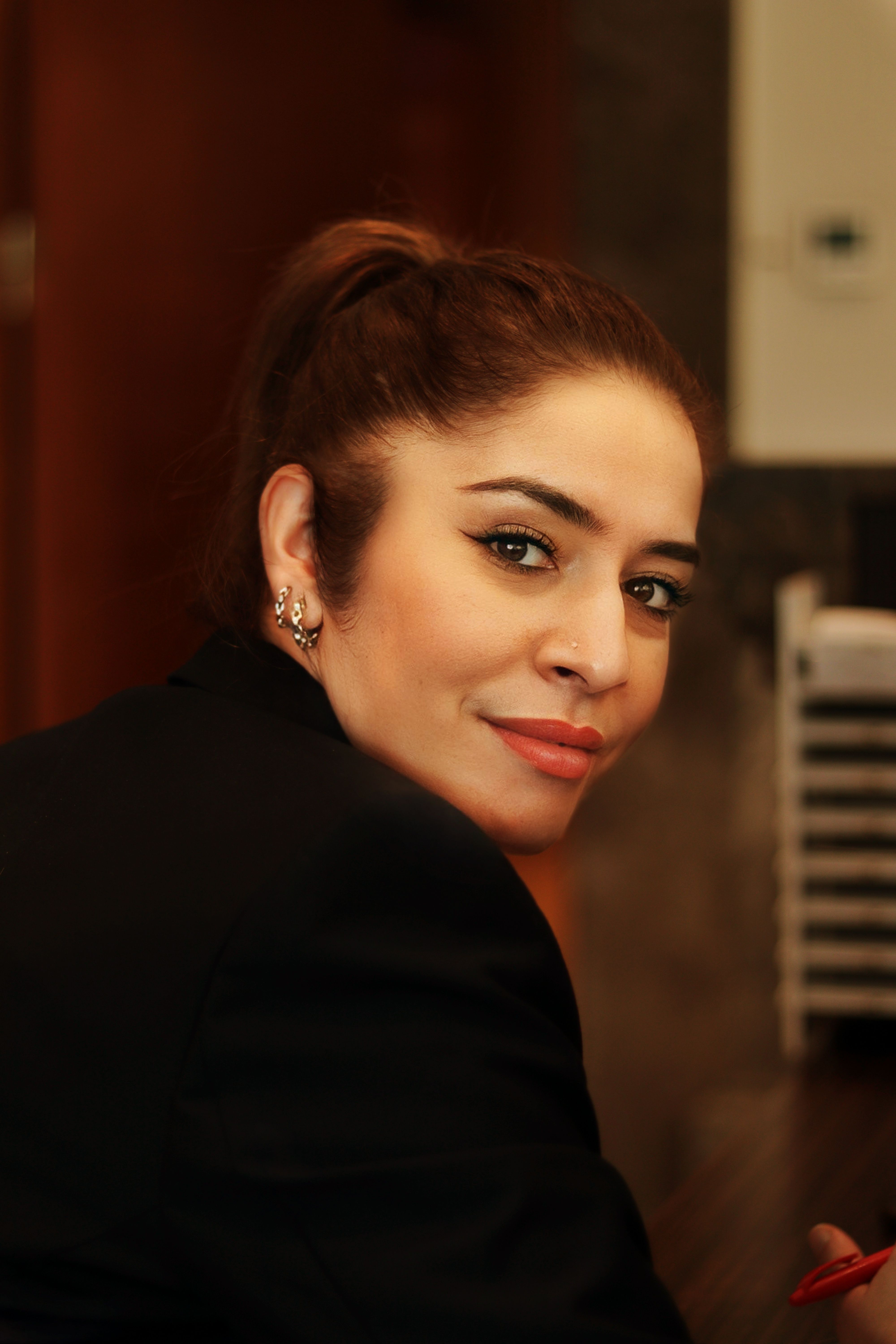 Elegant woman with a ponytail looking over her shoulder in a thoughtful expression.