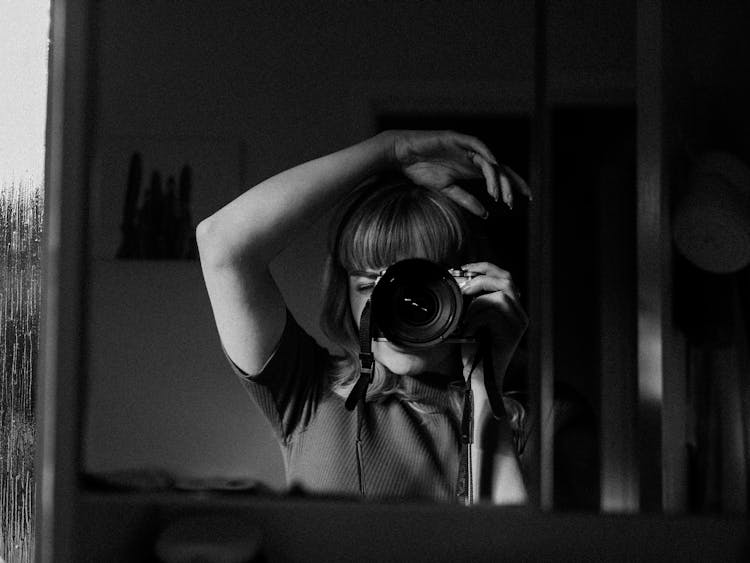 Reflection Of Woman Taking Pictures With Camera In Mirror