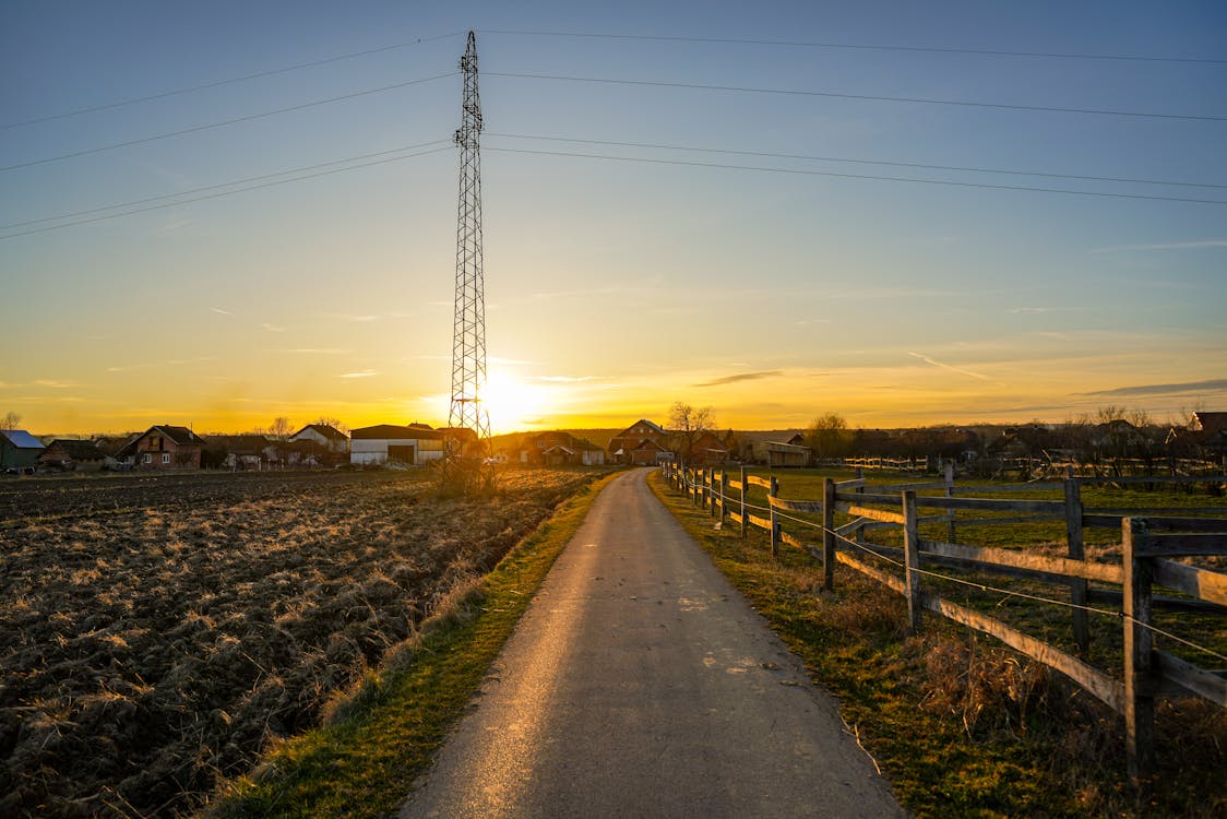 A road with a fence and telephone poles in the distance