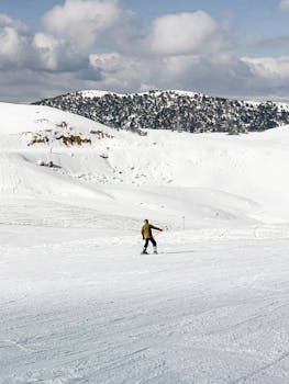 A person skiing on a snow-covered mountain under a cloudy sky, capturing winter adventure.