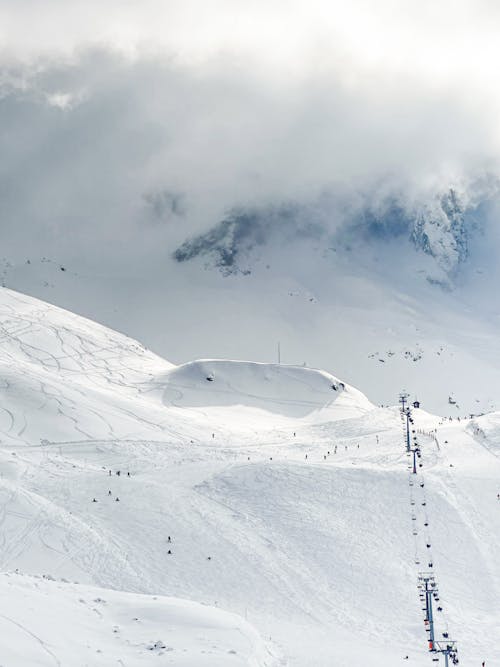 A snow covered mountain with people walking down the slope