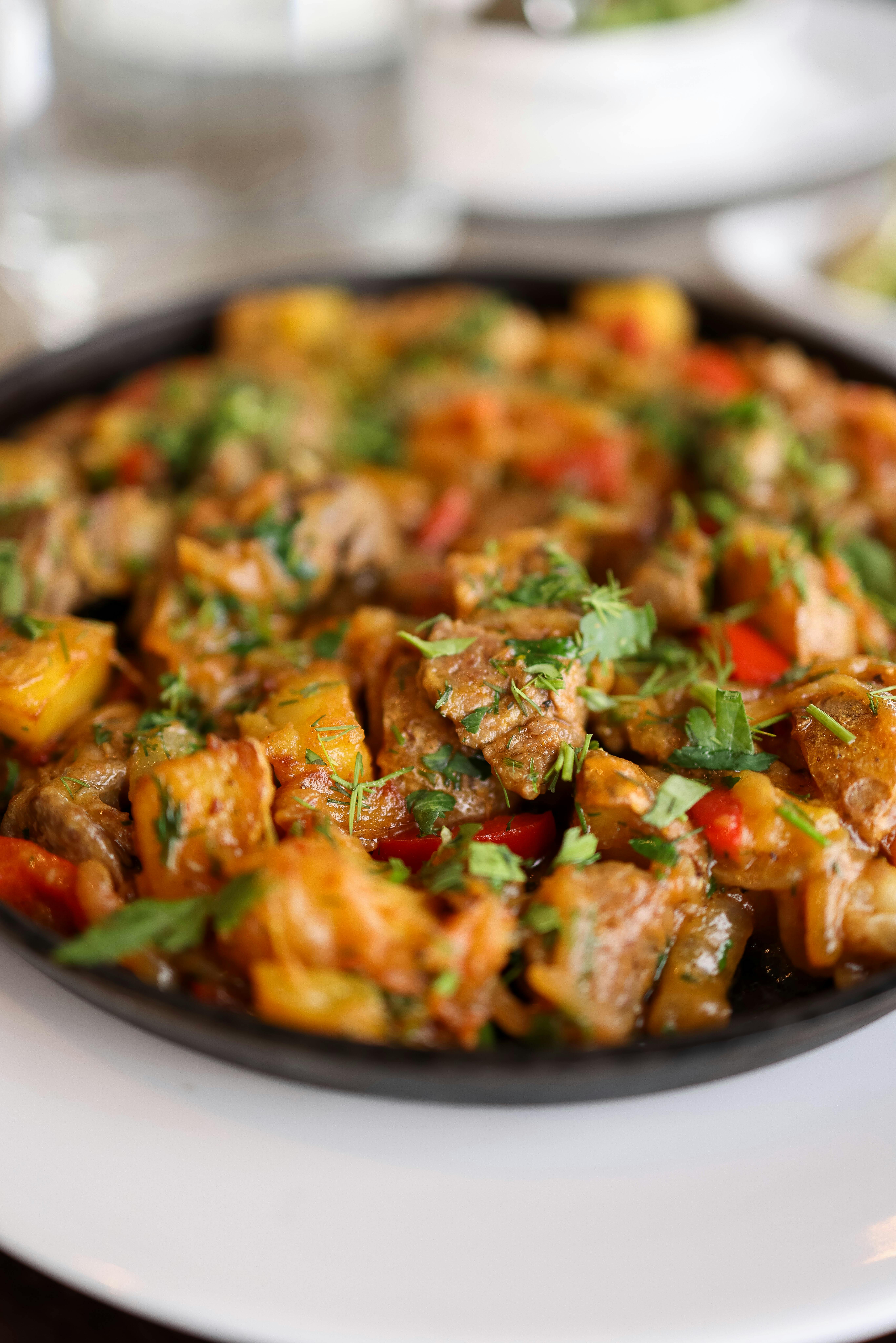 Colorful stir fry featuring meat and vegetables, garnished with herbs, served hot in a skillet.