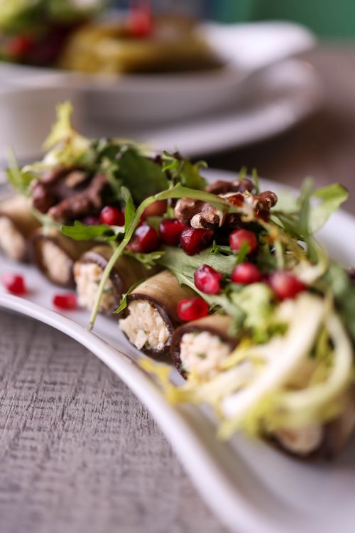 Free Delicious gourmet eggplant rolls garnished with pomegranate and greens, perfect for a Mediterranean meal. Stock Photo
