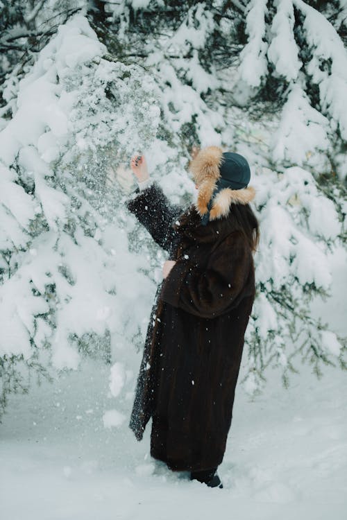 A woman in a fur coat is throwing snowballs