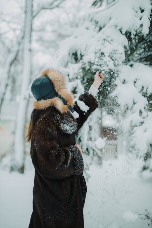 A woman in a fur coat is throwing snow